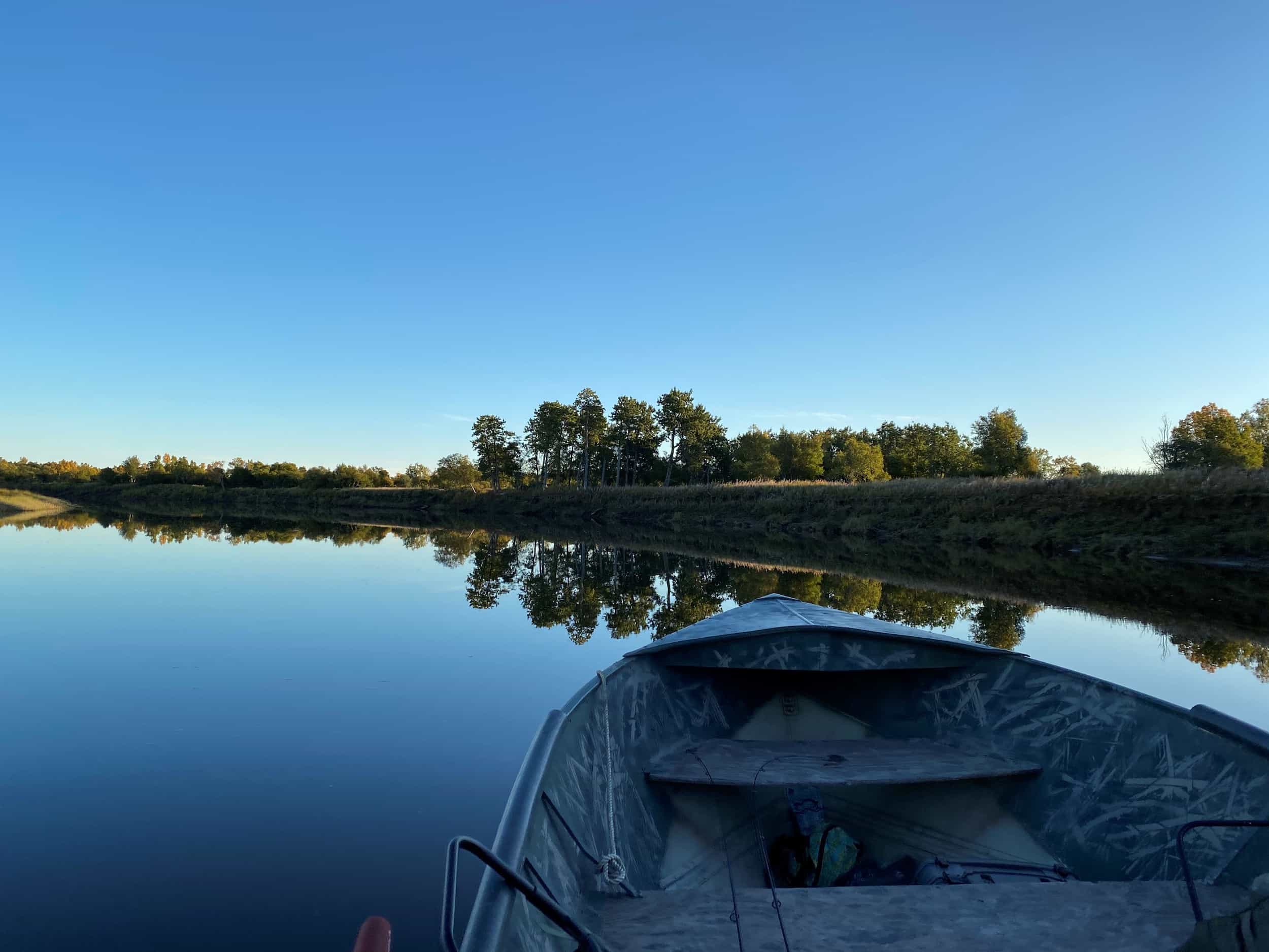 A boat sits on the Nushagak River on a clear and calm day. The boat faces the shore. This image is decorative. 